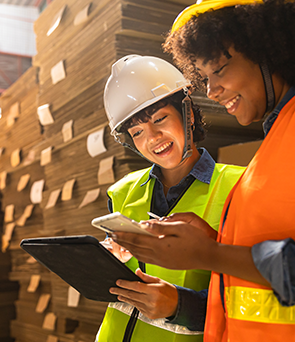Two warehouse workers looking at a tablet device and smiling